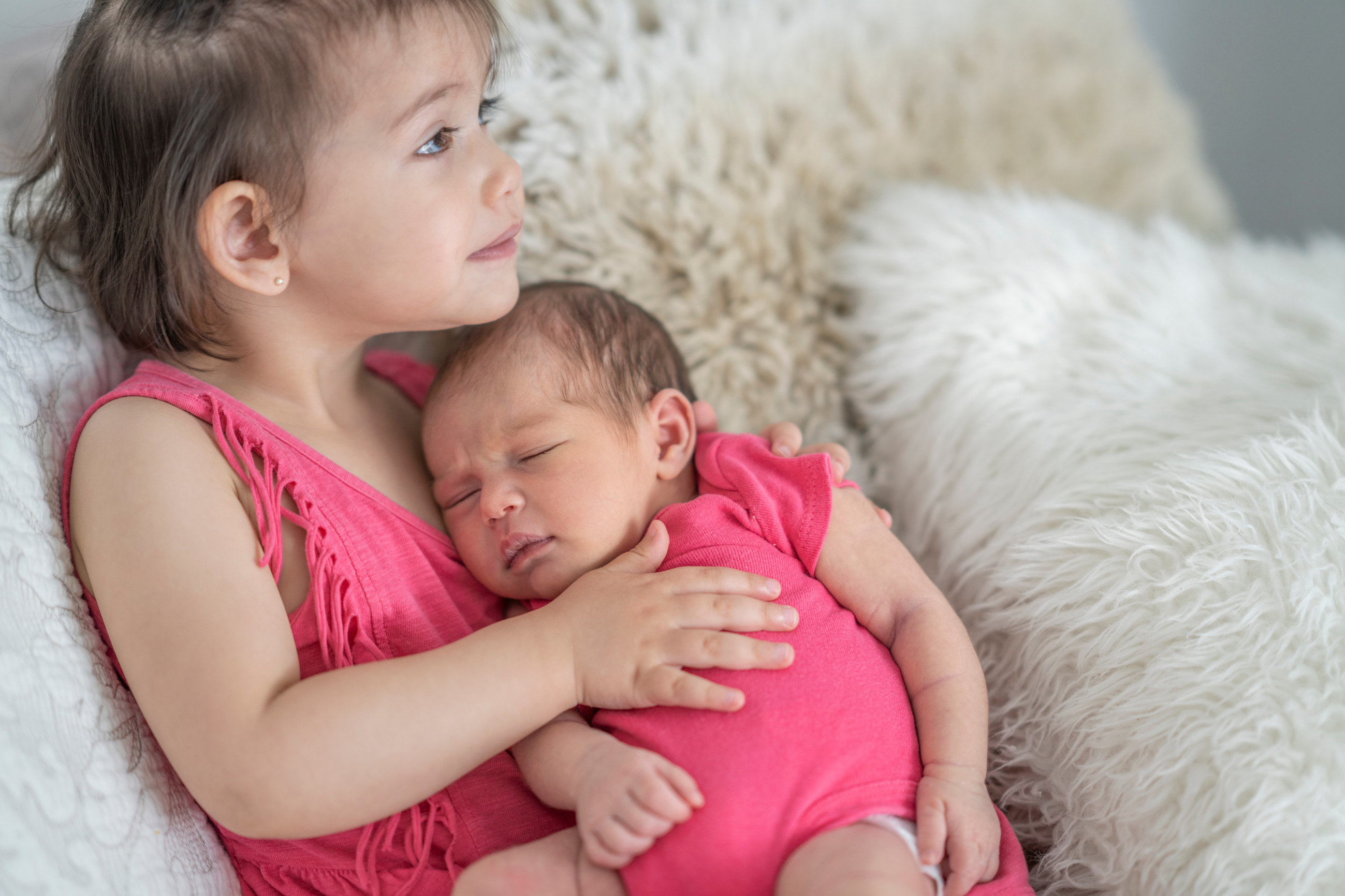 Proud big sister holding her newborn sibling